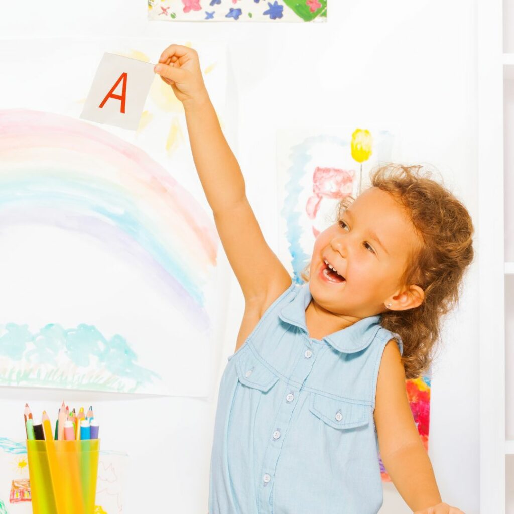 girl showing alphabet flashcards